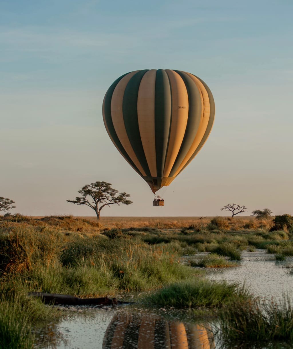 A hot-air balloon over a floodplain at first light, reflected in the water