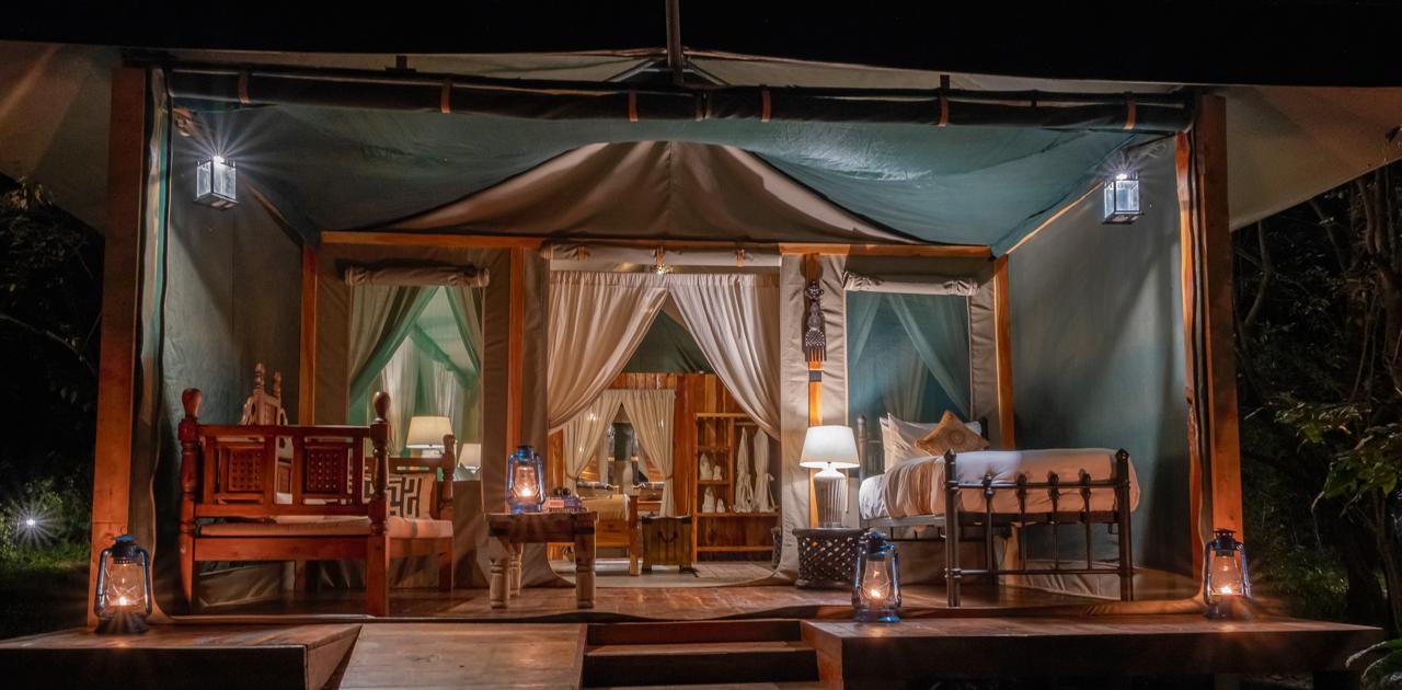 A warmly lit luxury safari tent at night