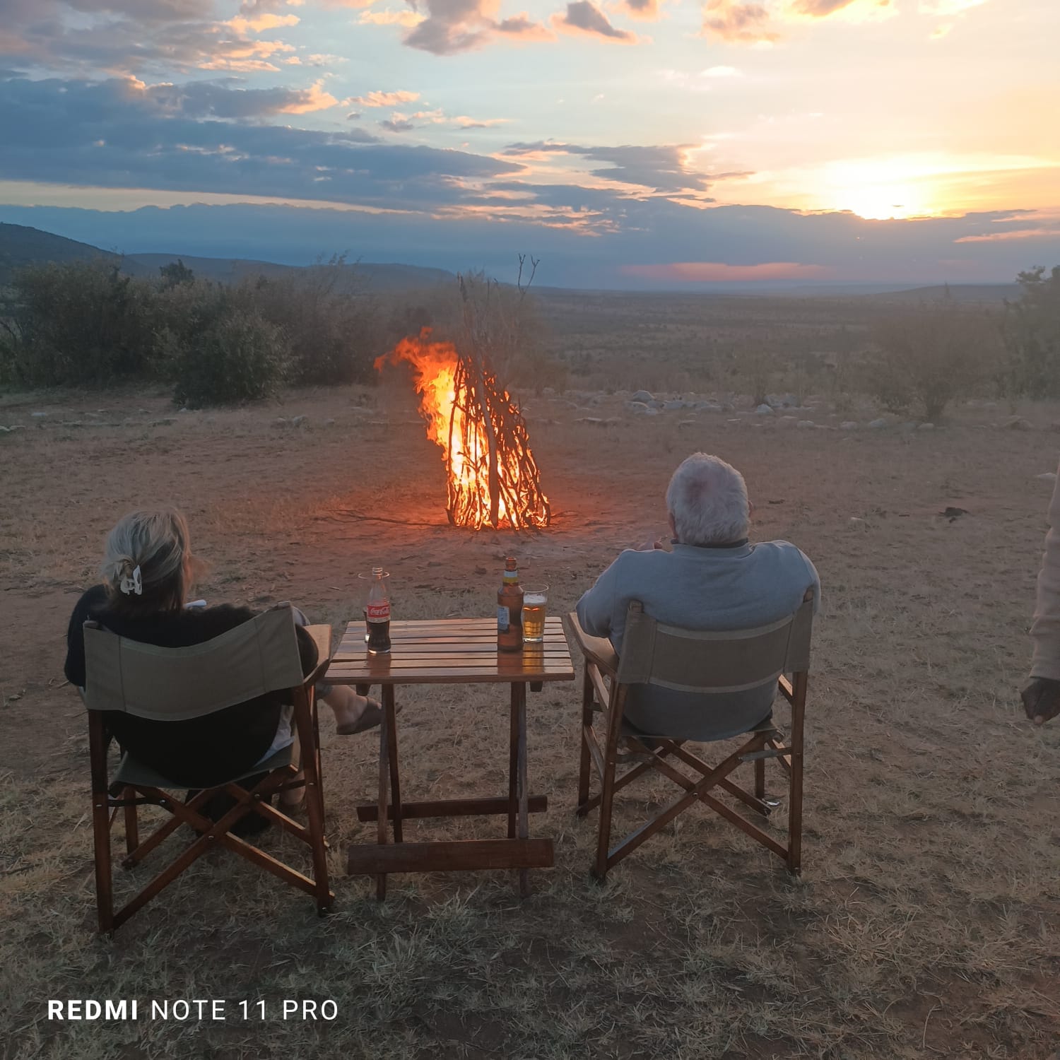Two travellers by a campfire at sunset on safari