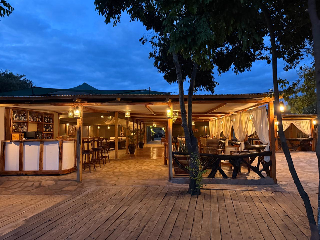 An open-air safari camp lounge at dusk